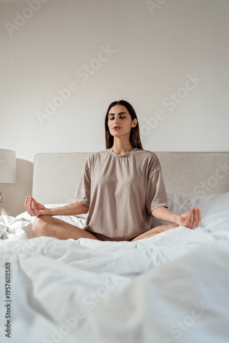 Young woman meditating in bed at home, mindfulness and mental health concept
