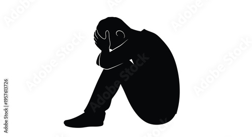 Despondent figure seated with head in hands a stark silhouette
