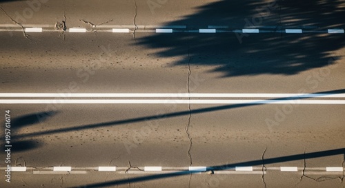 Aerial View Of An Asphalt Road With Tree Shadows And Lane Markings