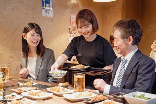 Фотография 居酒屋で料理を提供する女性スタッフ