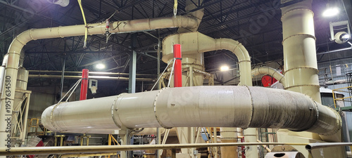 Cuadro en lienzo Spacious interior of an industrial factory showing large wood particle transport ducts, explosion and dust suppression systems, piping and structural machinery in a manufacturing facility