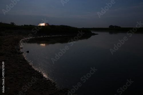 illuminated tent next to a river at night in germany