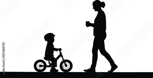 Silhouette of woman walking with child on balance bike