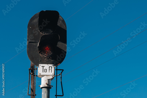 Railway signal with red light against a clear blue sky