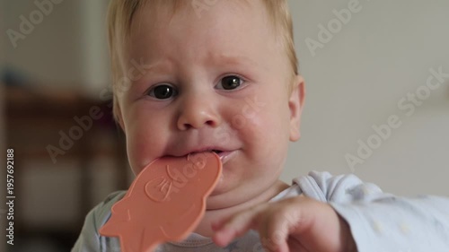 Baby chewing pink fish teether playfully, closeup. Candid home interior soft natural light, curious expression drool gum rubbing oral exploration early teeth milestone parenting moment toy discovery