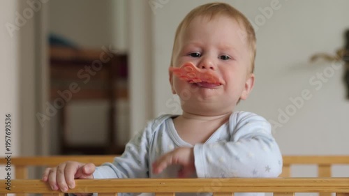 Joyful teething moment. Adorable infant enjoying first teething experiences in cozy nursery setting. Cute baby chewing teether with messy lips while exploring textures in peaceful morning environment