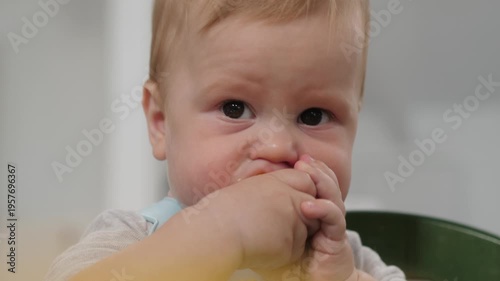 Baby eats corn. Child exploring tasty kernels happily. Young infant delights in munching on corn kernels. Young baby happily tastes corn while displaying curiosity and cheerful playfulness in demeanor