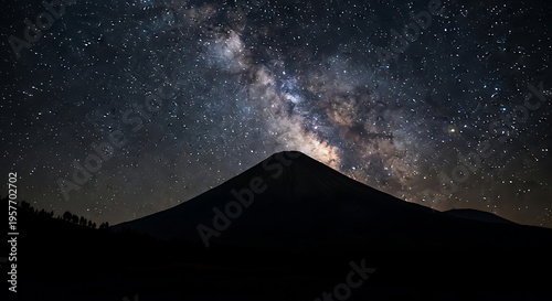 A breathtaking view of the Milky Way galaxy arching majestically over a silhouetted mountain peak under a star-filled night sky