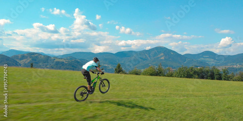 AERIAL Unrecognizable man speeds down a single trail on a green electric bicycle