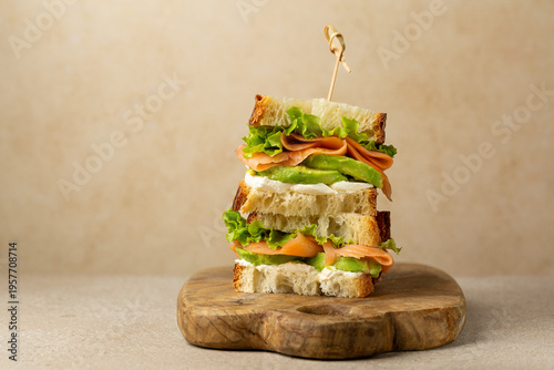 Stack of Club sandwiches with Smoked Salmon fish, lettuce, avocado and cream cheese , beige background. Copy space.