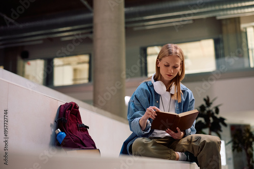 Foto University student studying from book at lecture hall.