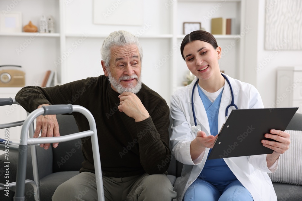 Obraz premium Care worker with clipboard talking to senior man indoors