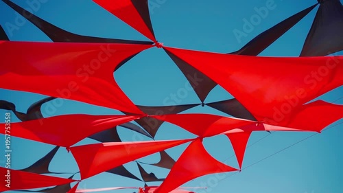 abstract view of red and black triangle shaped cloth decoration waving by wind on blue sky background. summer sea camp or beach club decoration, vibrant colors