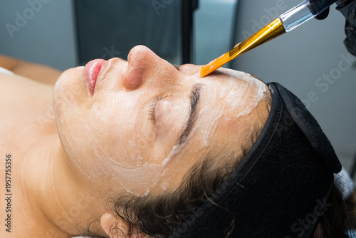 Woman receiving facial peeling with brush applicator