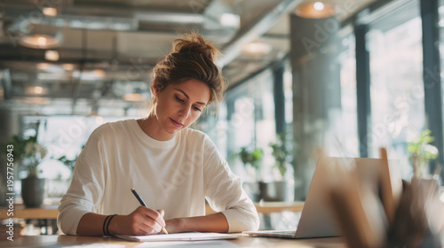 Young professional woman in casual smart outfit filling out a job application form at a modern coworking space desk, medium shot, natural window light, soft shadows, clean minimal interior, laptop and