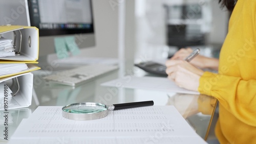 Foto A woman in a yellow blouse performs financial calculations and reviews paperwork as part of a business tax audit in her office