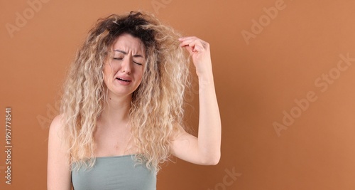 Φωτογραφία Unhappy woman with tangled damaged hair on brown background, space for text