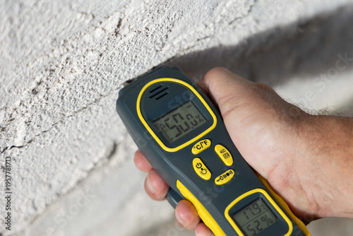 Moisture Meter measuring the moisture level of an exterior wall of a house, close up hand
