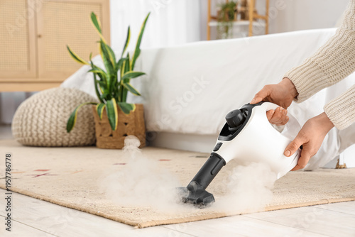 Female hands steam cleaning carpet in bedroom