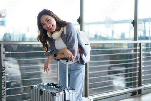 Smiling female traveler with luggage at airport terminal