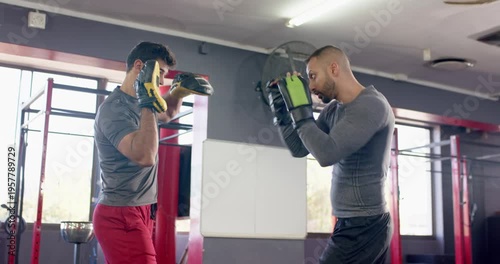 Trainer raising focus mitts signalling indian trainee throwing punches at boxing gym training
