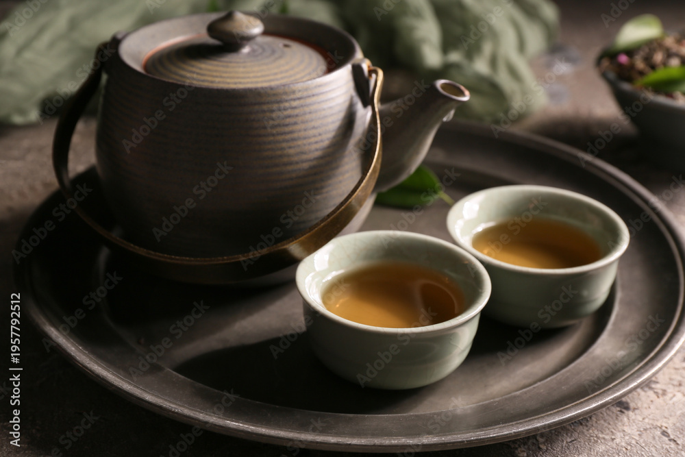 Fototapeta premium Tray, teapot and cups of green tea on grey grunge background, closeup