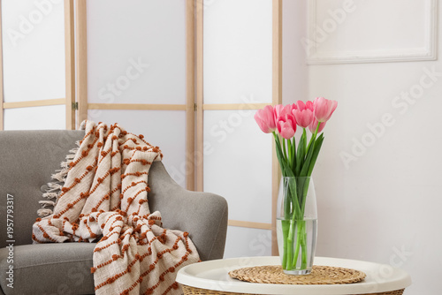Vase with tulips for Women's Day on table in light living room