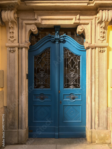 Blue wooden door with decorative metalwork set in stone archway in historic building in city during daytime