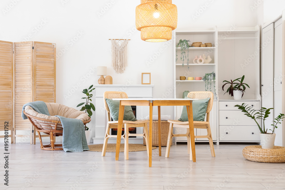 Fototapeta premium Interior of stylish dining room with table, armchair, fireplace and glowing lamp
