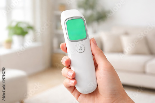 Woman holding a digital thermometer with a blank green screen for telemedicine and digital health concept. Remote medical device, blank screen, mockup, copy space
