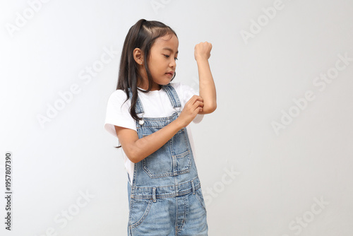 Fotografi A 7-8 year old Asian child scratches his itchy hand due to mosquito bites or dermatitis, scabies, allergy symptoms, or malaria