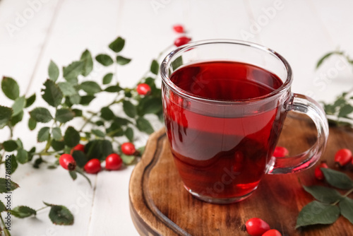 Canvastavla Glass cup of hot rose hip tea and berries on white wooden background, closeup