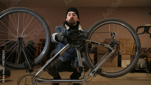 Fotografija Man focusing on repairing bicycle drivetrain, performing maintenance and adjusti