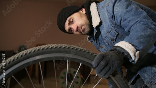Photography Man in beanie and fur collared denim jacket trying to stealthily remove a bicycl