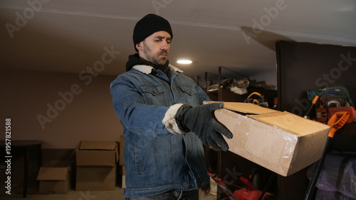 Canvas Print Male thief wearing a black beanie and denim jacket with gloves, carefully carryi