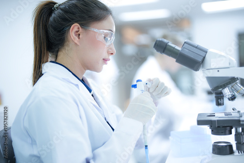 Tableau sur toile Focused female pathologist using a microscope to examine tissue biopsy samples in a sterile hospital laboratory