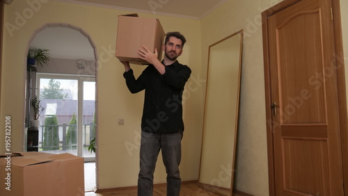 Photos Man moving into a new home, carrying a large cardboard box on his shoulder, symb