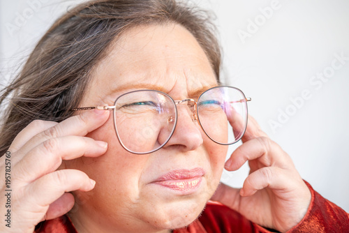Close up portrait mature woman adjusting glasses, squinting with discomfort, eye strain, vision problem, headache or migraine symptom, health and eyesight issue, digital fatigue, Health awareness
