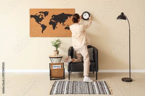Young woman hanging clock o...
