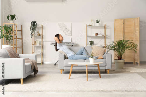 Young beautiful woman resting on cozy sofa in living room