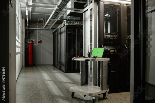 Φωτογραφία Empty server room featuring metal racks with network equipment, green laptop and