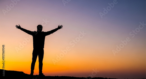 Silhouette of a man with outstretched arms against a vibrant sunset sky.