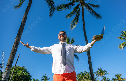 Businessman on summer. Online freelance work. Successful businessman worker. Vacation work setup. Business man using laptop among palm tree. Business trip success. Man freelance worker online