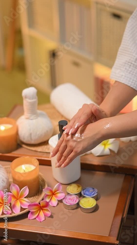 Closeup women applying lotion in spa room with warm light and calm wellness.