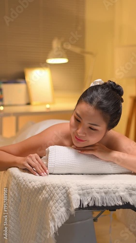 Young woman enjoying relaxing massage therapy at spa, lying on massage table.