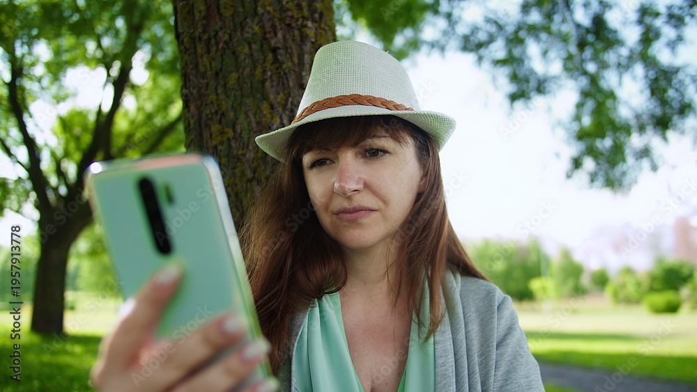 Fototapeta premium Young Woman Using Smartphone Outdoors in Park, have fun and enjoy