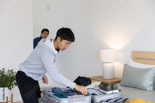 Canvastavla Asian father and son packing suitcase on bed in bedroom with gray hoodie sneaker