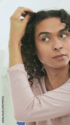 Vertical video: Zooming in, person touching hair and applying cream for grooming at bathroom mirror