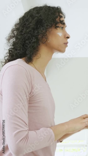 Vertical video: Opening jar nonbinary adult applying cream at vanity for skincare wearing pink top