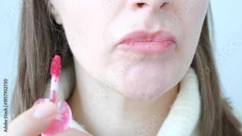 Young woman applying bright pink lipstick to her lips front view close-up.